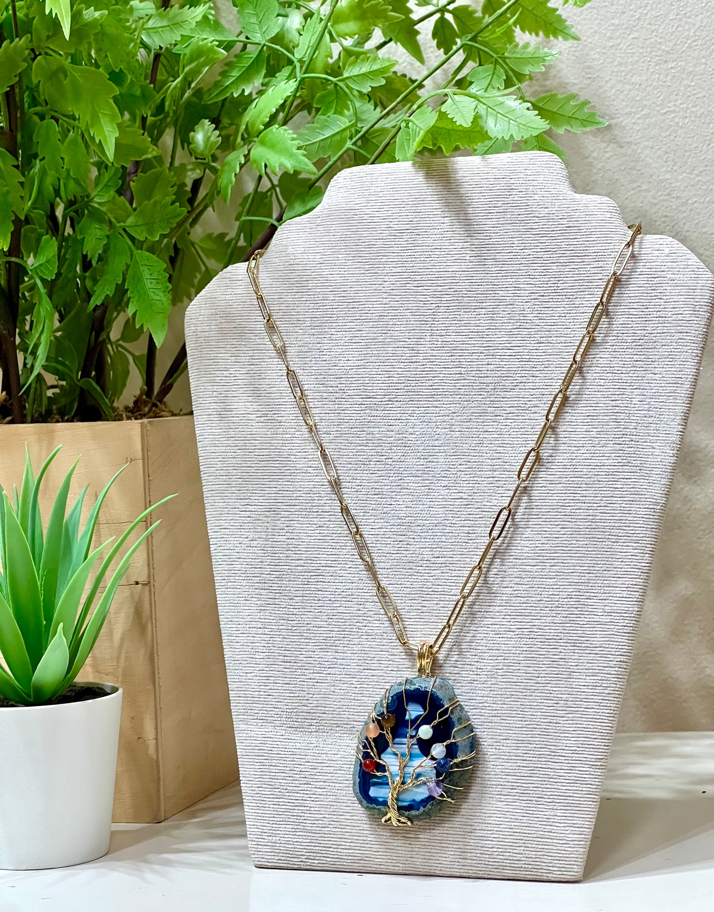 Collar acero y piedra natural sobre árbol